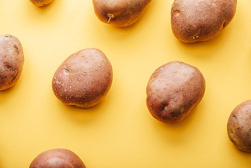 pattern of raw whole fresh potatoes on yellow background