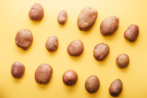 top view of raw whole fresh potatoes on yellow background