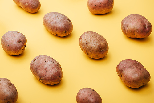 pattern of raw whole fresh potatoes on yellow background