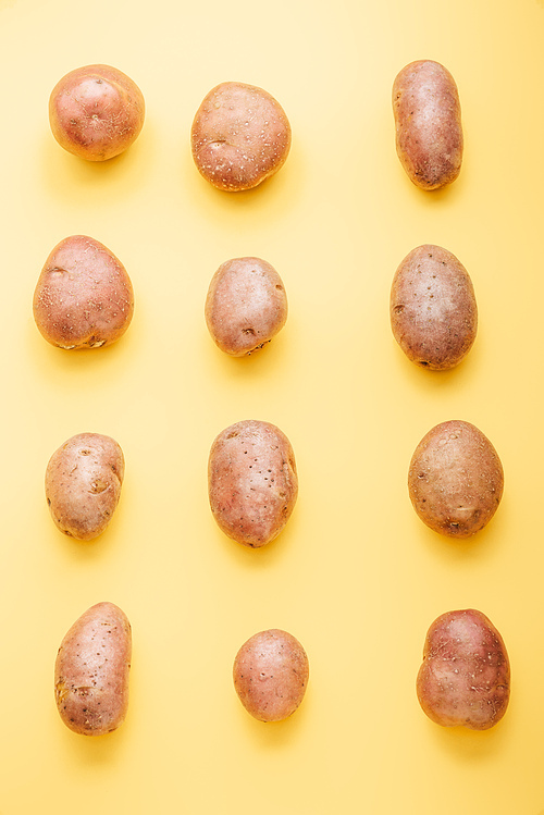 top view of raw whole fresh potatoes on yellow background