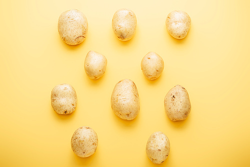 top view of raw whole fresh potatoes on yellow background