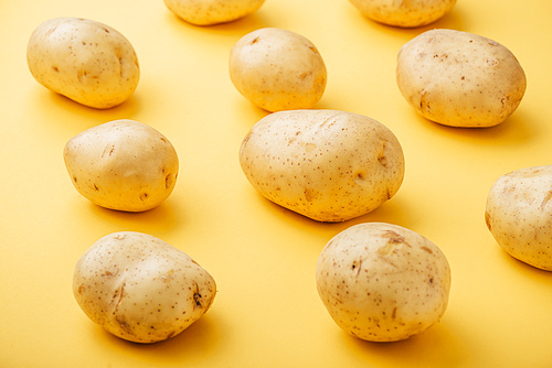 pattern of raw whole fresh potatoes on yellow background