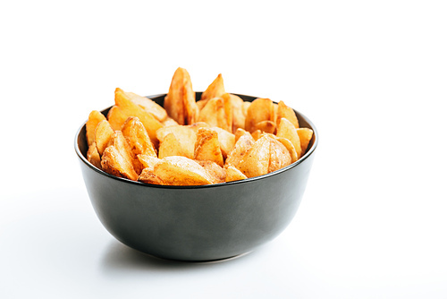 delicious golden potato wedges in bowl on white background