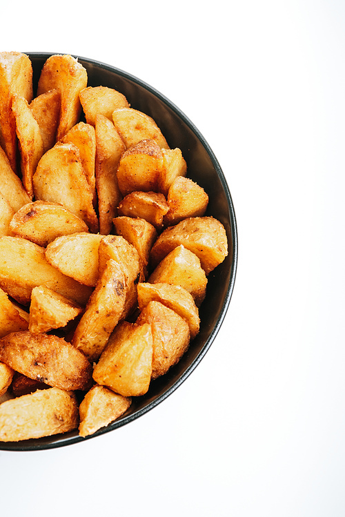 top view of delicious golden potato wedges in bowl isolated on white