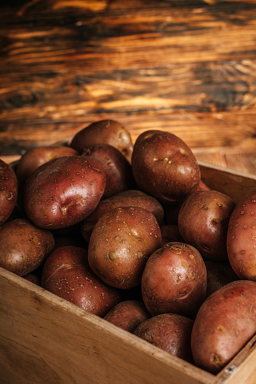 close up view of fresh ripe potatoes in box on wooden background