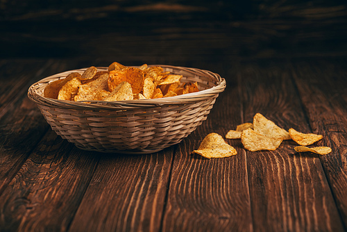 delicious crispy potato chips in wicker basket on wooden table