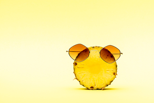 delicious sweet cut pineapple in sunglasses on yellow background