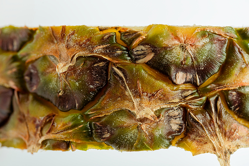 close up view of pineapple slice with brown textured peel isolated on white