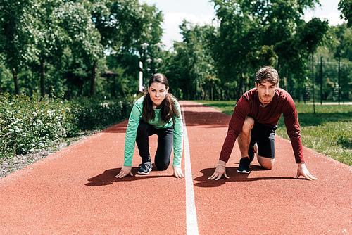 Couple standing in starting position on running track in park