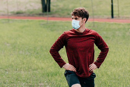 Sportsman in medical mask working out in park