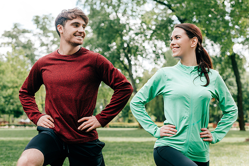 Young couple smiling at each other while training together in park