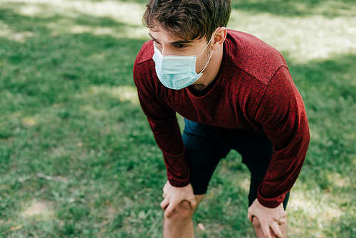 Young sportsman in medical mask standing in park
