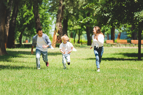 happy family in casual clothes running in park during daytime