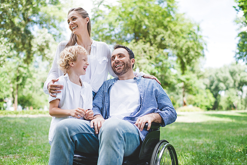 happy family with disabled father on wheelchair in park