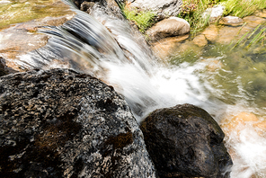 steam with water flowing on rocks near grass in park