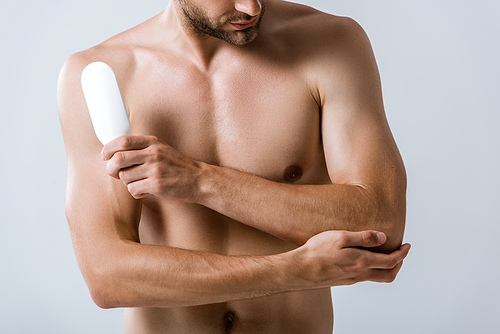 cropped view of shirtless man holding bottle of ointment and touching elbow isolated on grey