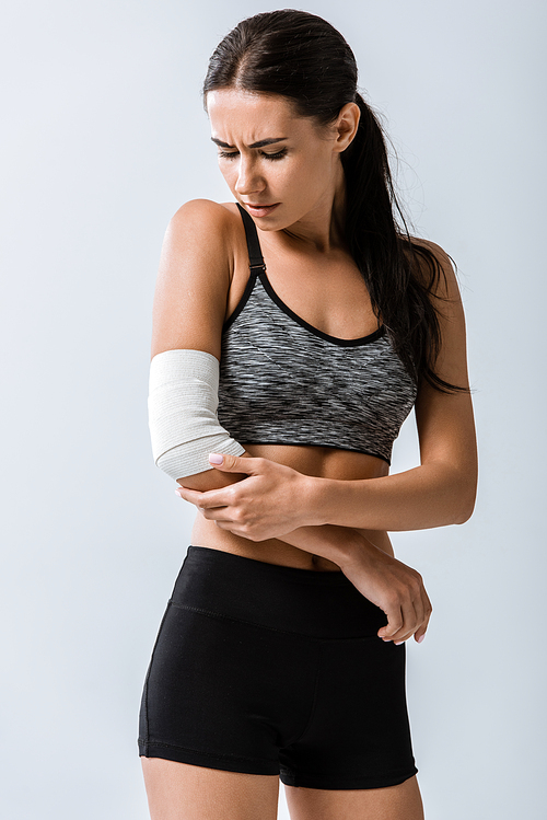 sportswoman with elastic bandage on elbow isolated on grey