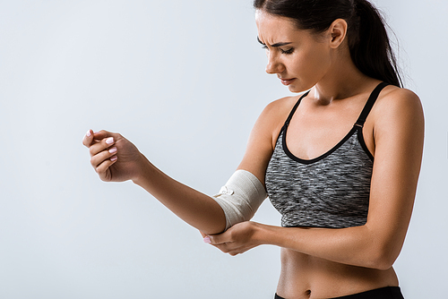 sportswoman with elastic bandage on elbow isolated on grey