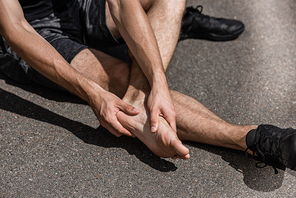 partial view of barefoot sportsman with foot pain on street