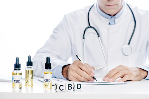 cropped view of doctor in white coat writing with pen isolated on white