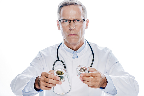 handsome doctor in white coat holding medical cannabis and pills isolated on white