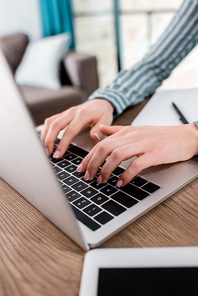 cropped view of young freelancer typing on laptop keyboard