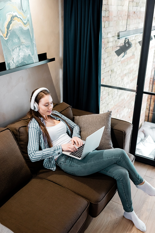 attractive freelancer in wireless headphones using laptop in living ...