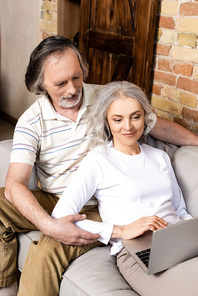 happy and mature freelancers using laptop at home