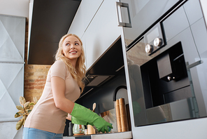 smiling housewife looking away while washing dishes in kitchen