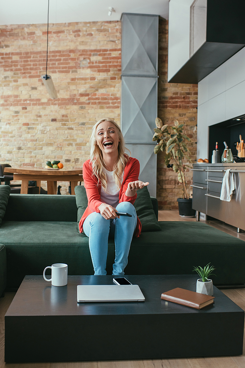 excited woman laughing while watching tv at home
