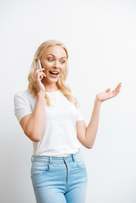 happy woman talking on smartphone while standing with open arm isolated on white