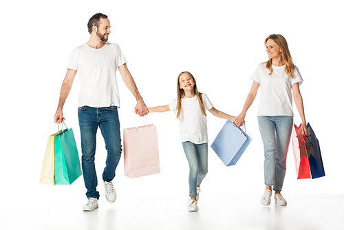 cheerful family walking with colorful shopping bags and holding hands isolated on white
