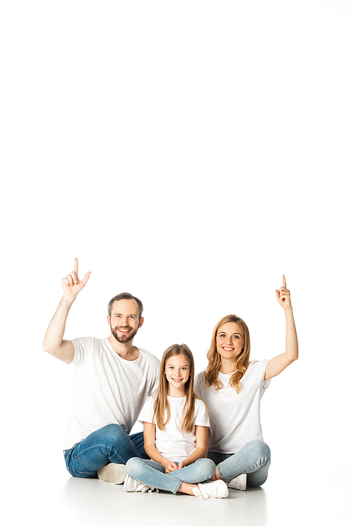 happy family sitting on floor with crossed legs and pointing up isolated on white
