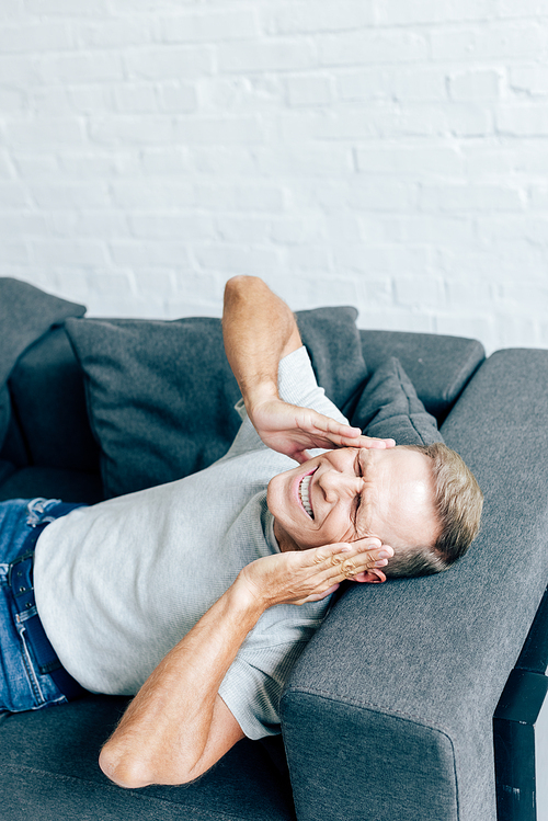 high angle view of handsome man in t-shirt with closed eyes touching head in apartment