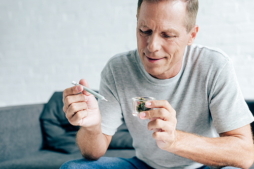 handsome man in t-shirt holding blunt and medical cannabis