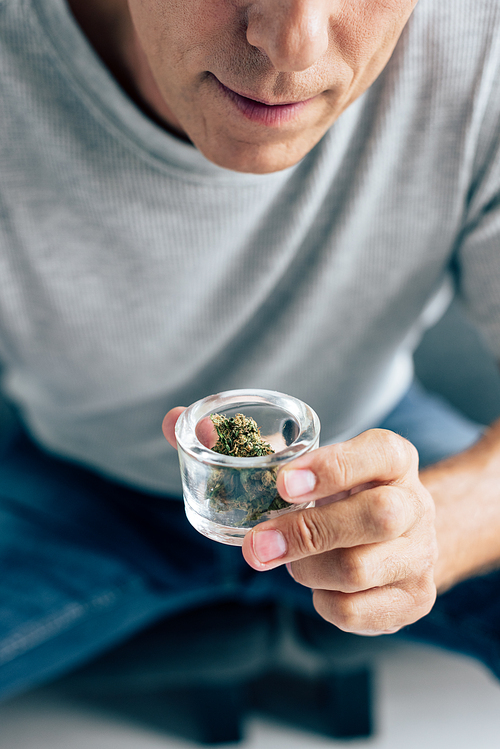 cropped view of man in t-shirt looking at medical cannabis in apartment