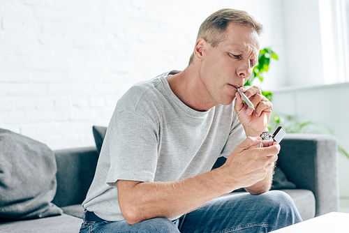 handsome man in t-shirt lighting up blunt with medical cannabis