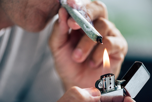 cropped view of man lighting up blunt with medical cannabis