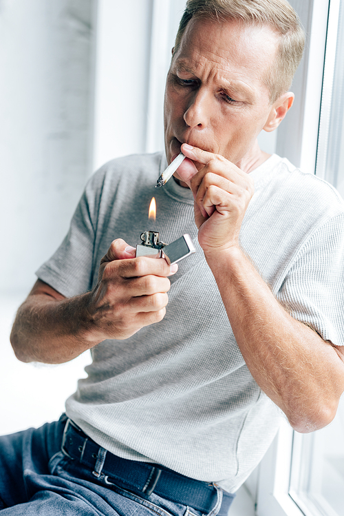 handsome man lighting up blunt with medical cannabis in apartment