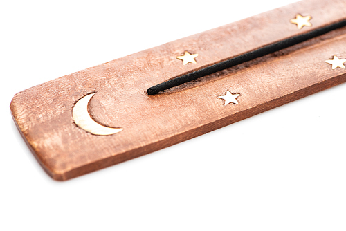 close up view of aroma stick on wooden stand with moon and stars on white background