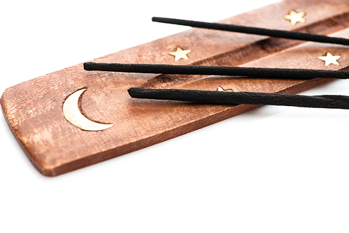 close up view of aroma sticks on wooden stand with moon and stars on white background