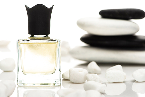 selective focus of home perfume in bottle near spa stones on white background