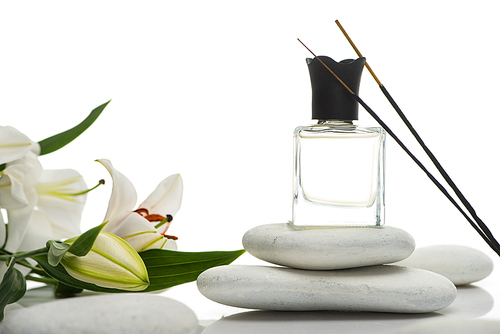 aroma sticks and perfume on spa stones near lilies isolated on white