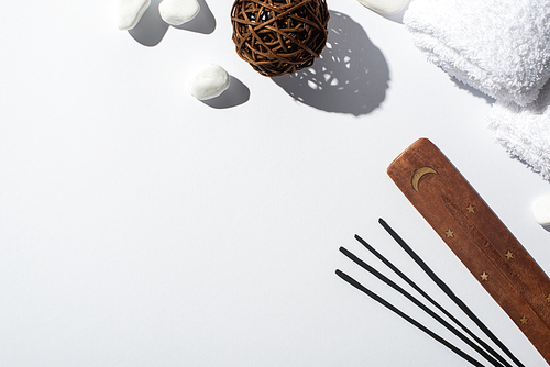 top view of aroma sticks, wooden stand, stones, cotton towels and decorative ball on white background