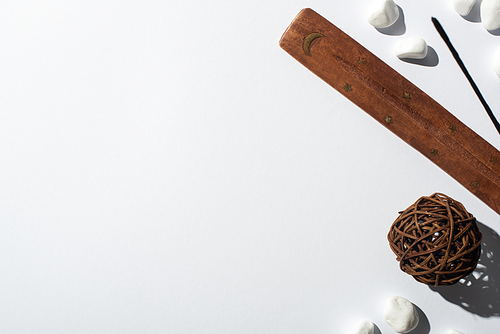 top view of aroma stick, stones, wooden stand and decorative ball on white background