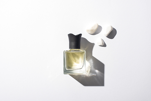 top view of home perfume in bottle near stones on white background