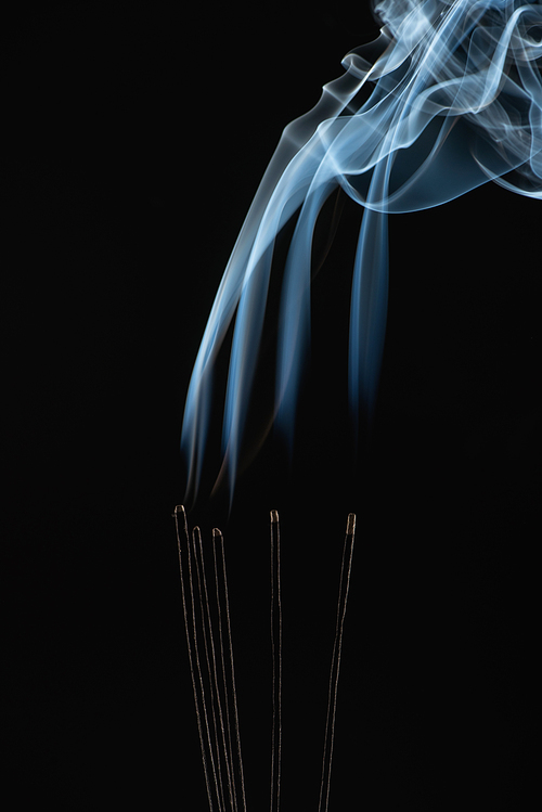 burning aroma sticks with smoke on black background