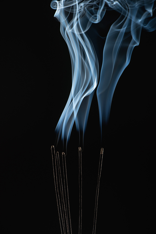burning aroma sticks with smoke on black background