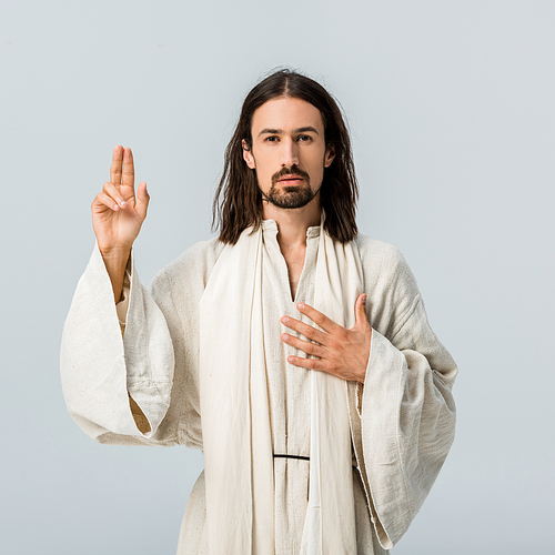 handsome man praying with hand on chest isolated on grey