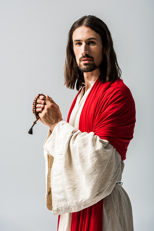 handsome religious man holding rosary beads isolated on grey